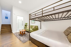 Ein Schlafzimmer mit Etagenbetten, einem grünen Sofa, einem kleinen Tisch und einer Duschkabine aus Glas.