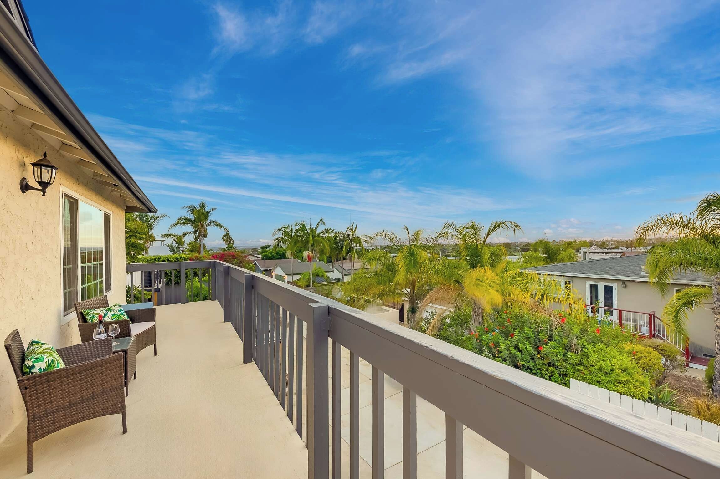 A balcony with wicker furniture and a view of a residential area.