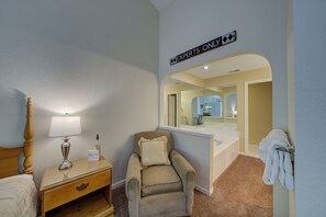 A hotel room with a bed, a nightstand with a lamp, a chair, a bathroom with a sink and mirror, and a sign that reads 'EXPERTS ONLY'. - Dreams and Streams at Pinebrook- Your Perfect Northern Michigan Escape! (Bellaire)