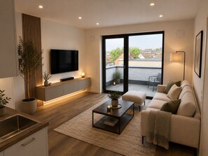 Ein modernes Wohnzimmer mit Flachbildfernseher, einer Couch, einem Couchtisch und einem Balkon mit Blick.
