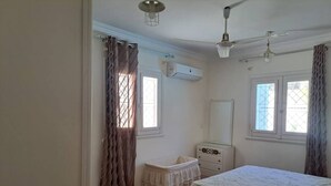 A bedroom with a bed, a dresser, a mirror, and a window with curtains. - Villa Cranzy: 3BR with private pool, bianki, AL agami, Alexandria ,Egypt (Alexandria Governorate)