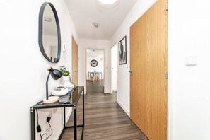 A hallway with wooden doors, a round mirror, a desk with a lamp, and a clock on the wall. - Stylish 1-bed flat | Free parking | Fast Wi-Fi (Basingstoke)