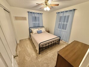 A bedroom with a bed, a ceiling fan, and a wooden dresser. - 2-bedroom house in pleasant Rolla with cool AC for relaxing stays (Rolla)