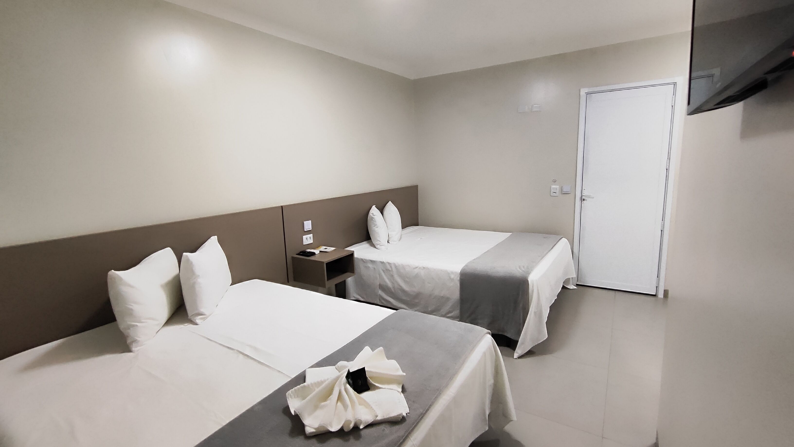 Ein Hotelzimmer mit zwei Betten, einem Nachttisch und einer Tür.
