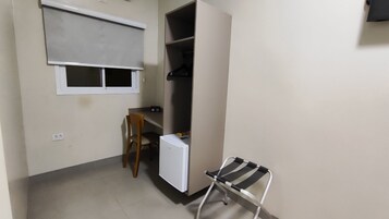 A small room with a desk, a chair, a wardrobe, and a window.