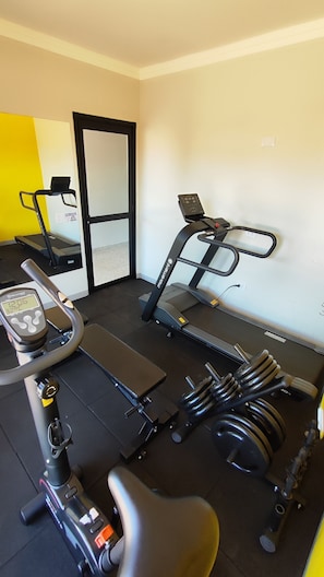 A gym with exercise equipment including a treadmill, stationary bike, and weights. - Star Hotel Express (Água Clara)
