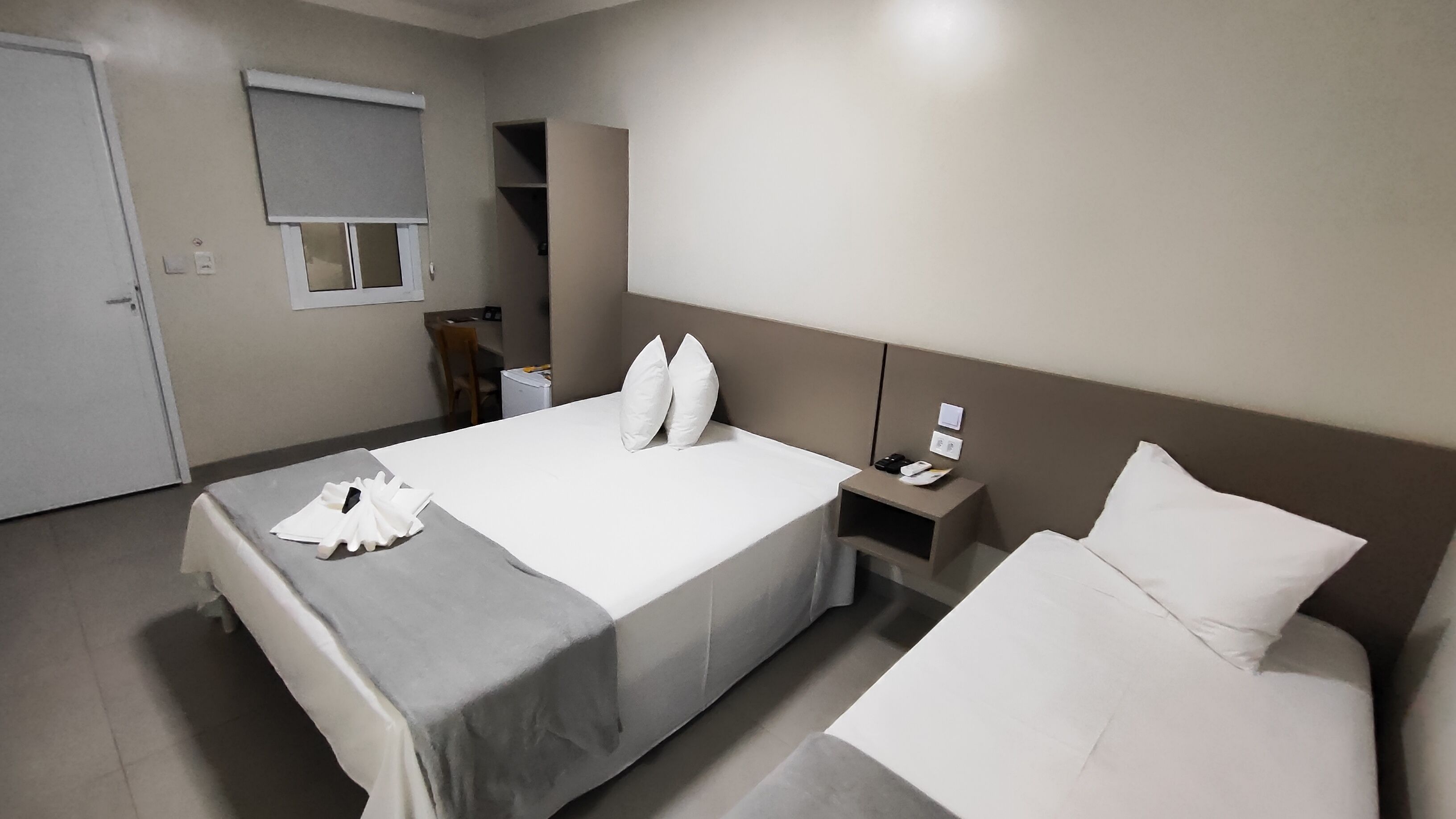 A hotel room with a bed, bedside table, and a chair.
