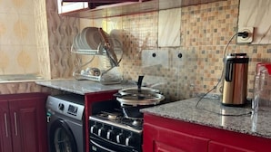A kitchen with a washing machine, stove, and a coffee maker on the countertop. - Luxury and Classy with City View (Yaoundé)