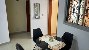 A dining area with a table and chairs, a decorative mirror, and a window with decorative iron bars. - Luxury and Classy with City View (Yaoundé)