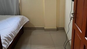 A bedroom with a bed, a window with curtains, a television mounted on the wall, and a wooden door. - Luxury and Classy with City View (Yaoundé)