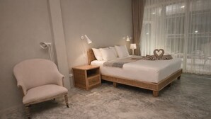 Ein Schlafzimmer mit einem Bett, einem Sessel, einem Nachttisch und einer Lampe.