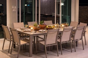 A dining table set for six with chairs, candles, and a fruit bowl.