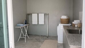 Ein kleines Badezimmer mit Dusche, einer kompakten Bügeleinrichtung und einem Waschbecken mit einer Granit-Arbeitsplatte.