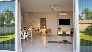 Ein modernes Wohnzimmer mit Fernseher, Deckenventilator und einem Wandbild.