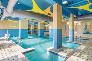 Ein Innenpool mit blauen und gelben Deckenmustern, gefliesten Wänden und klar abgetretenen Beckenrändern.