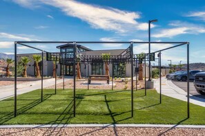 Ein modernes Gebäude mit Spielplatz, einer Sitzbank und einem Parkplatz.