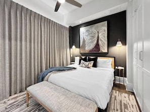 Ein Hotelzimmer mit einem großen Bett, einer Bank, einem Bild an der Wand und zwei Nachttischlampen.
