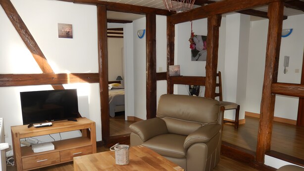 A living room with a wooden TV stand, a leather armchair, and a small wooden table.