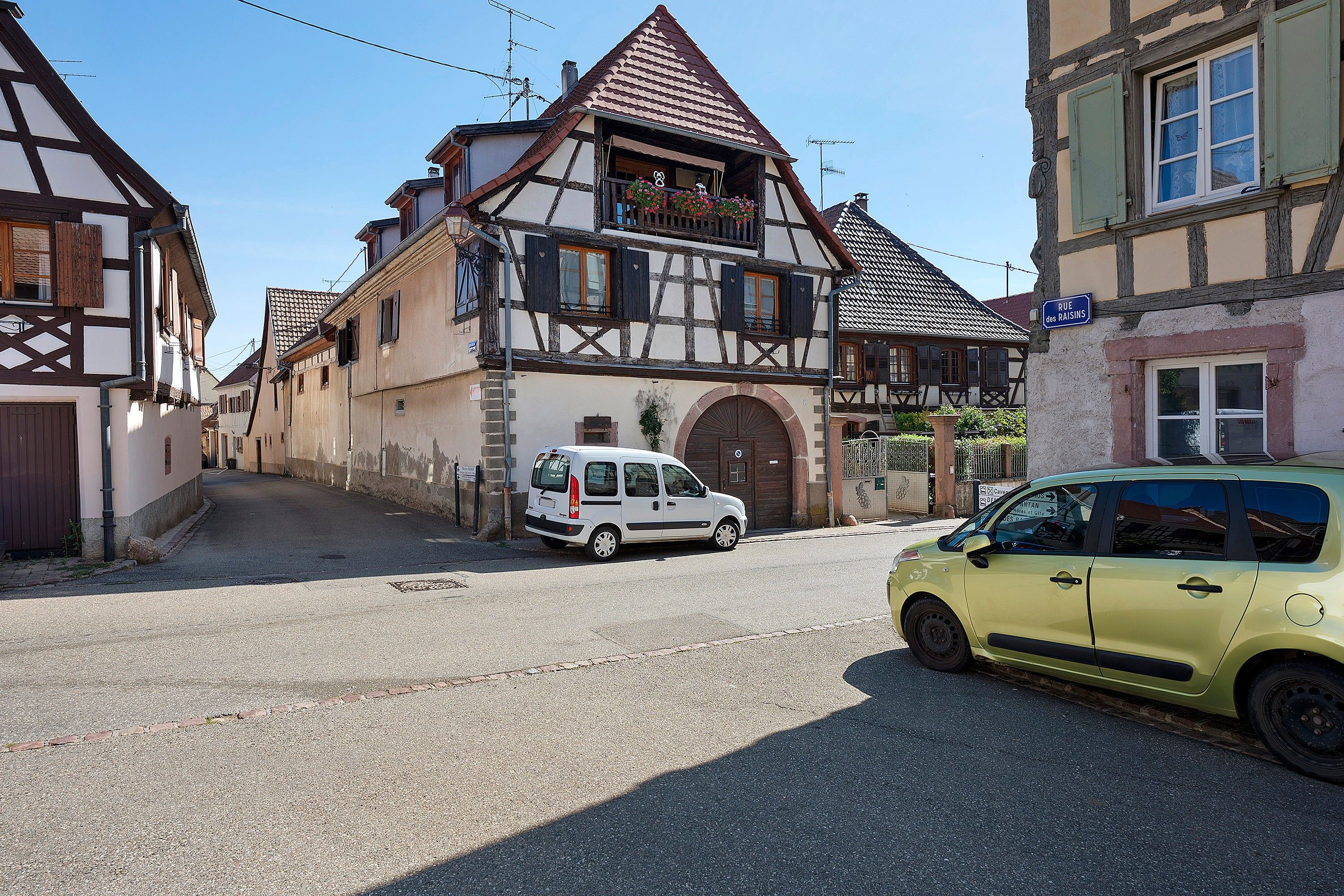 Une maison traditionnelle à colombages, avec un fourgon blanc garé devant.