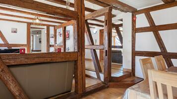 Quarto com vigas de madeira aparentes, uma janela grande e vista para o exterior.