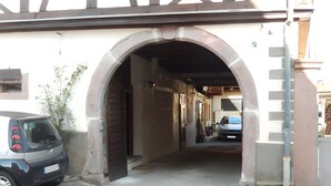 A narrow passageway with a small car parked on the left and a larger vehicle on the right.