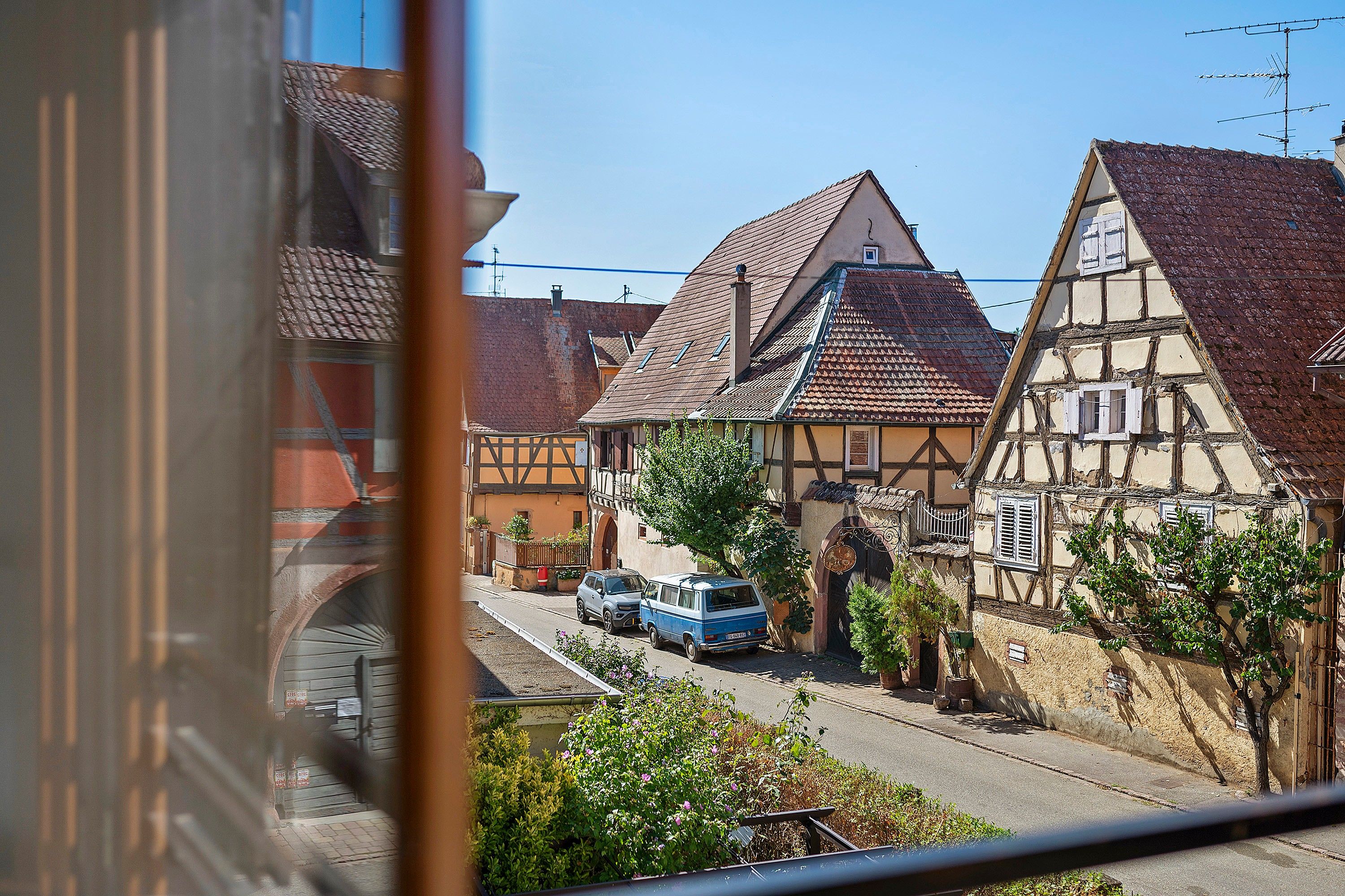 A traditional European street with half-timbered houses, a clear sky, and a parked van.