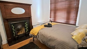 Ein Schlafzimmer mit einem Bett, einem Kamin und einem Fenster mit Jalousien.