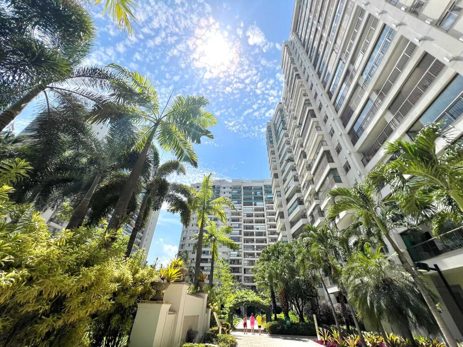 A multi-story building with a central courtyard surrounded by palm trees and other greenery.