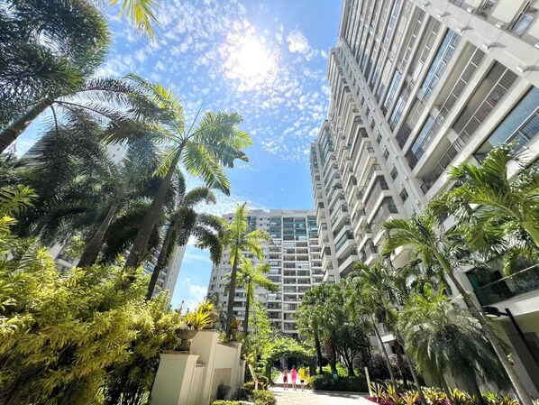 A multi-story building with a central courtyard surrounded by palm trees and other greenery. - Duplex penthouse in a luxury condominium. (Rio de Janeiro)