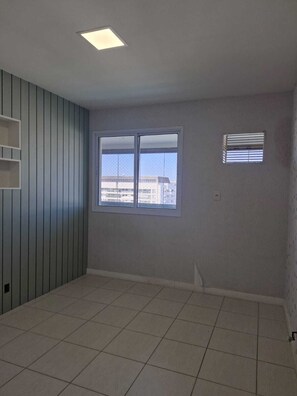 A room with a large window, a ceiling light, and a tiled floor. - Duplex penthouse in a luxury condominium. (Rio de Janeiro)