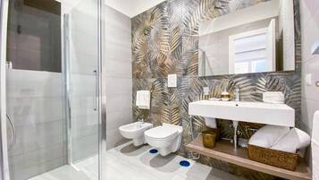 Un bagno moderno con box doccia in vetro, due servizi igienici, un lavabo con specchio e una decorazione a parete.