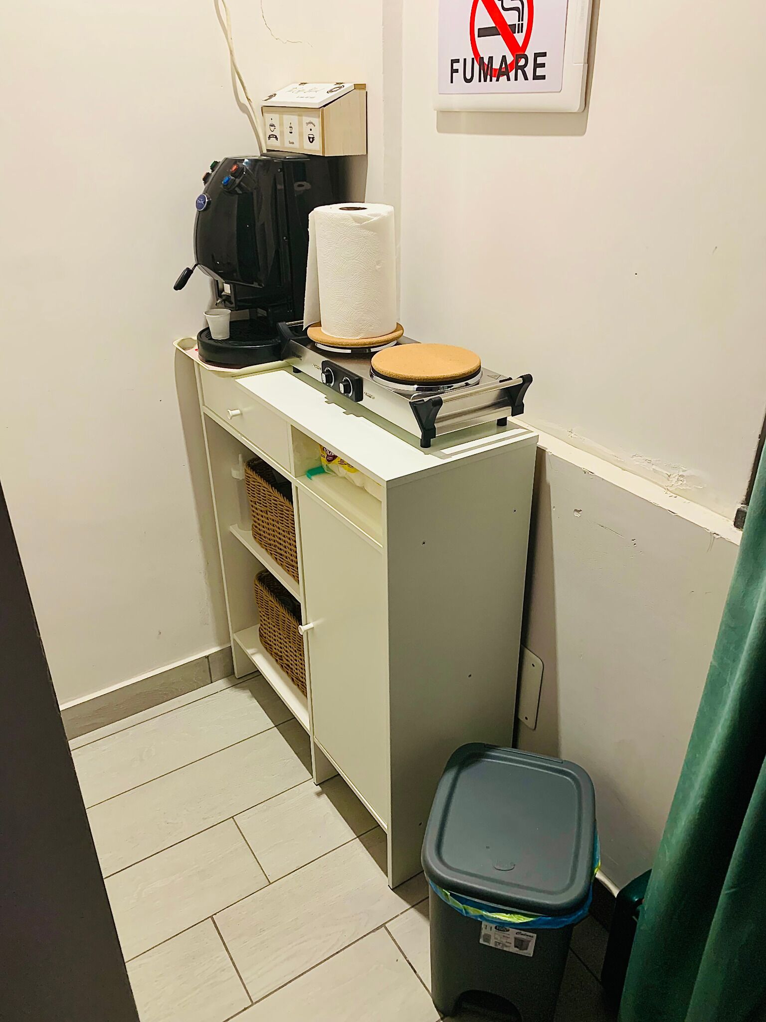 Un angolo cottura piccolo con una macchina da caffè, un dispenser di carta assorbente e un cestino.