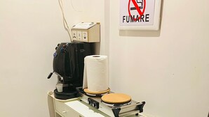 Eine kleine Küchenzeile mit Kaffeemaschine, Papierhandtuchspender und Mülleimer.