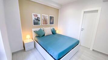 Una camera da letto con un letto, un comodino, una lampada a parete e una porta.
