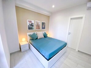 Une chambre à coucher avec un lit, une table de chevet, une lampe fixée au mur et une porte.