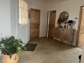 Ein Flur mit Holztüren, einem Blumentopf, einem Schrank mit Dekoration und einem gefliesten Boden.