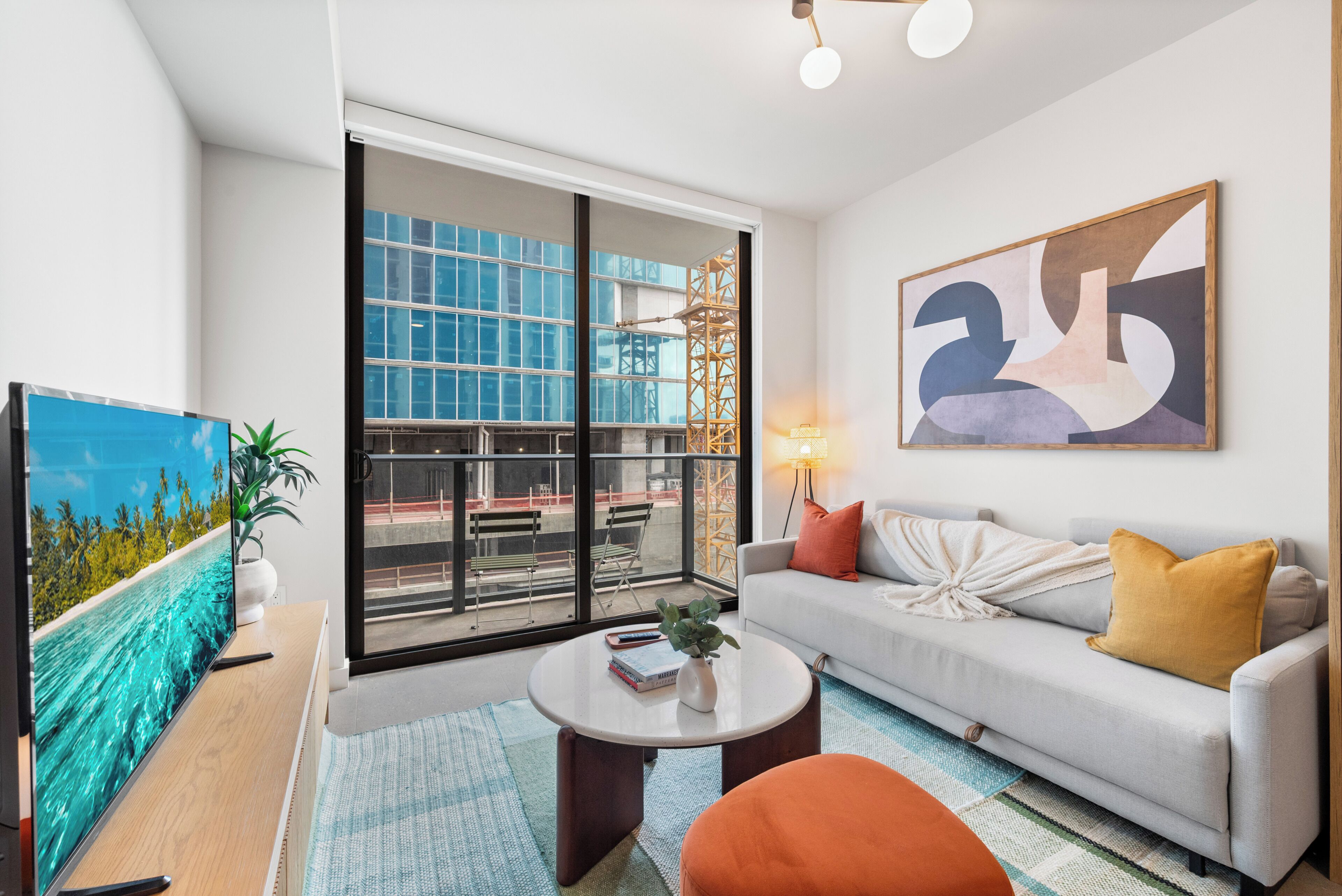 A modern living room with a large window, a sofa, a coffee table, and a painting.