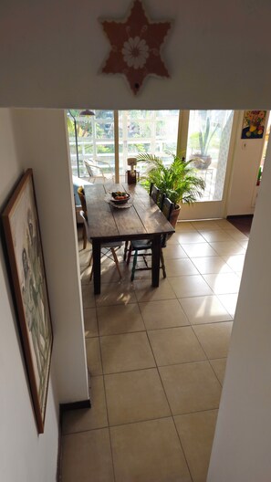 A dining area with a wooden table, chairs, a potted plant, and a star-shaped decoration on the wall. - House of Light (São Paulo)
