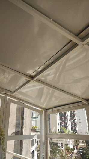 A ceiling with visible beams and a window with a view of a residential area. - House of Light (São Paulo)