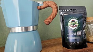 En blå kaffebryggare med ett handtag av trä och en påse med Pons de Lareds-kaffe.