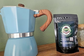 A blue coffee maker with a wooden handle and a bag of Pons de Lareds coffee.