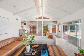 A spacious living area with a high ceiling, a large window overlooking a pool, and a seating arrangement with a sofa and a coffee table. -  Luxury gated villa with pool and stunning LA city views Prime Central location (Los Angeles)