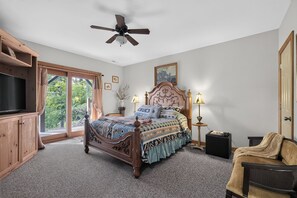 A bedroom with a wooden bed, a ceiling fan, a television, and a window with curtains. - Leatherwood MNT | Pinnacle Pt w/ 4-Stall Barn (Ferguson)