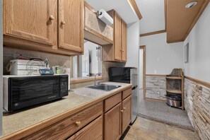 A kitchen with wooden cabinets, a microwave, a sink, and a refrigerator. - Leatherwood MNT | Pinnacle Pt w/ 4-Stall Barn (Ferguson)