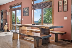 Un tavolo da pranzo in legno con panche in una stanza con ampie finestre e un quadro appeso al muro.