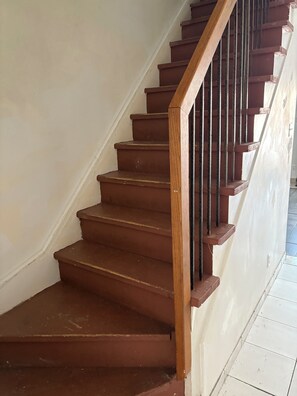 A wooden staircase with a black handrail leading to a landing.