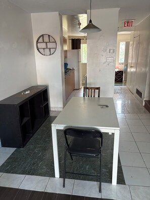 A dining area with a white table and chairs, a black bench, and a hanging light fixture. - Ideal place to get two floors at a great price (Toronto)