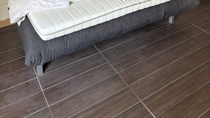 Sänky, jossa on punainen pääty, harmaa patja ja useita eri värisiä tyynyjä.