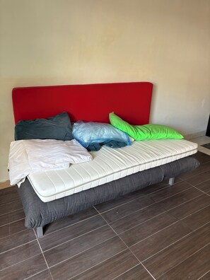A bed with a red headboard, grey mattress, and multiple pillows in various colors. - Ideal place to get two floors at a great price (Toronto)