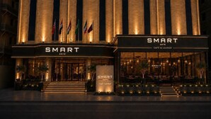 Entrada de hotel con señalización 'SMART GATE', varias banderas y fachada bien iluminada.